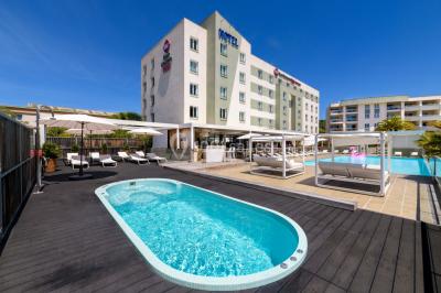 Ordinateur portable ouvert sur une table blanche avec carnet, tasse de café et plantes suspendues au-dessus.