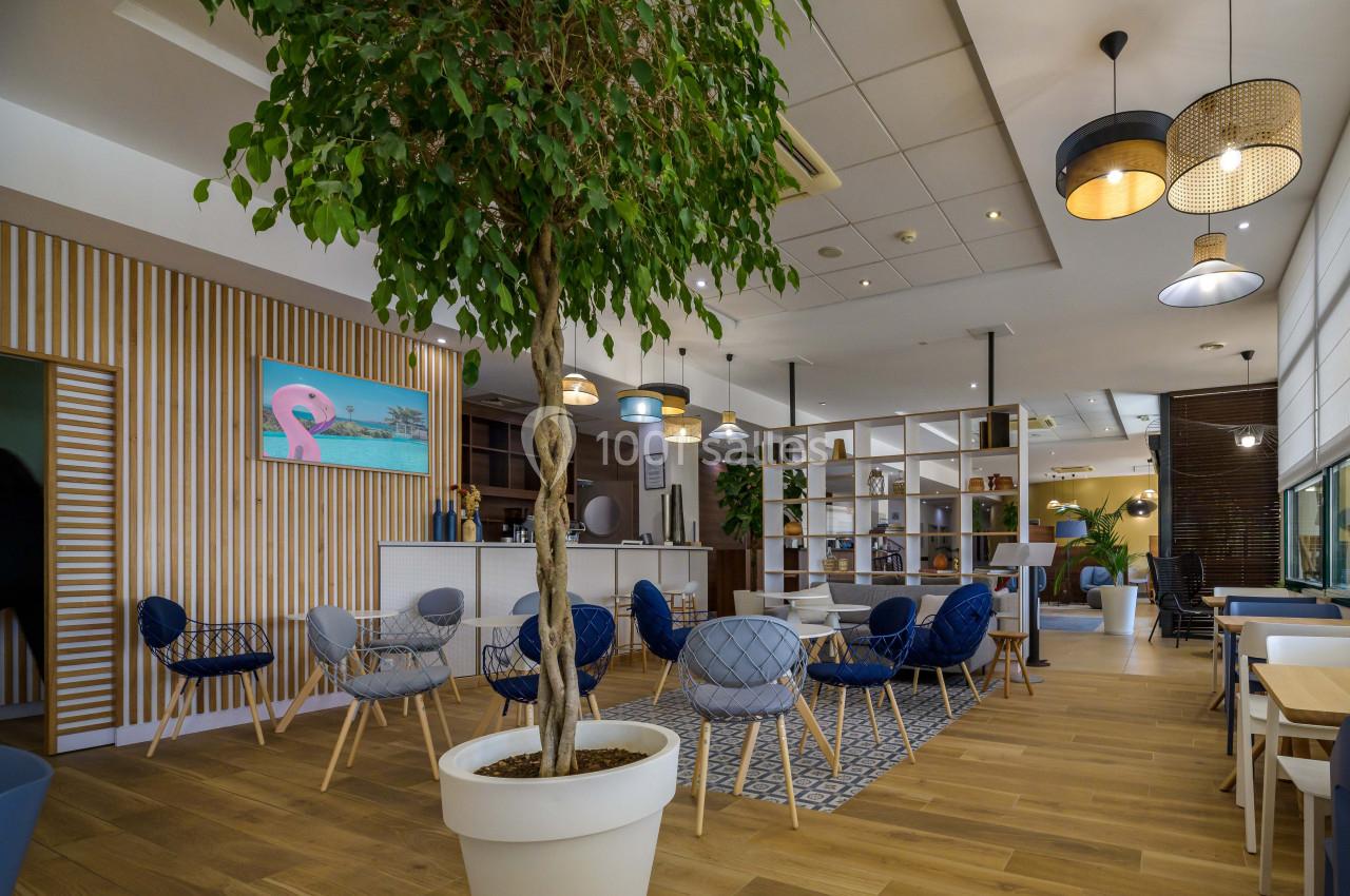 Espace intérieur lumineux avec des tables, des chaises modernes, un arbre en pot et une décoration contemporaine.