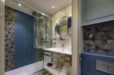 Ordinateur portable ouvert sur une table blanche avec carnet, tasse de café et plantes suspendues au-dessus.