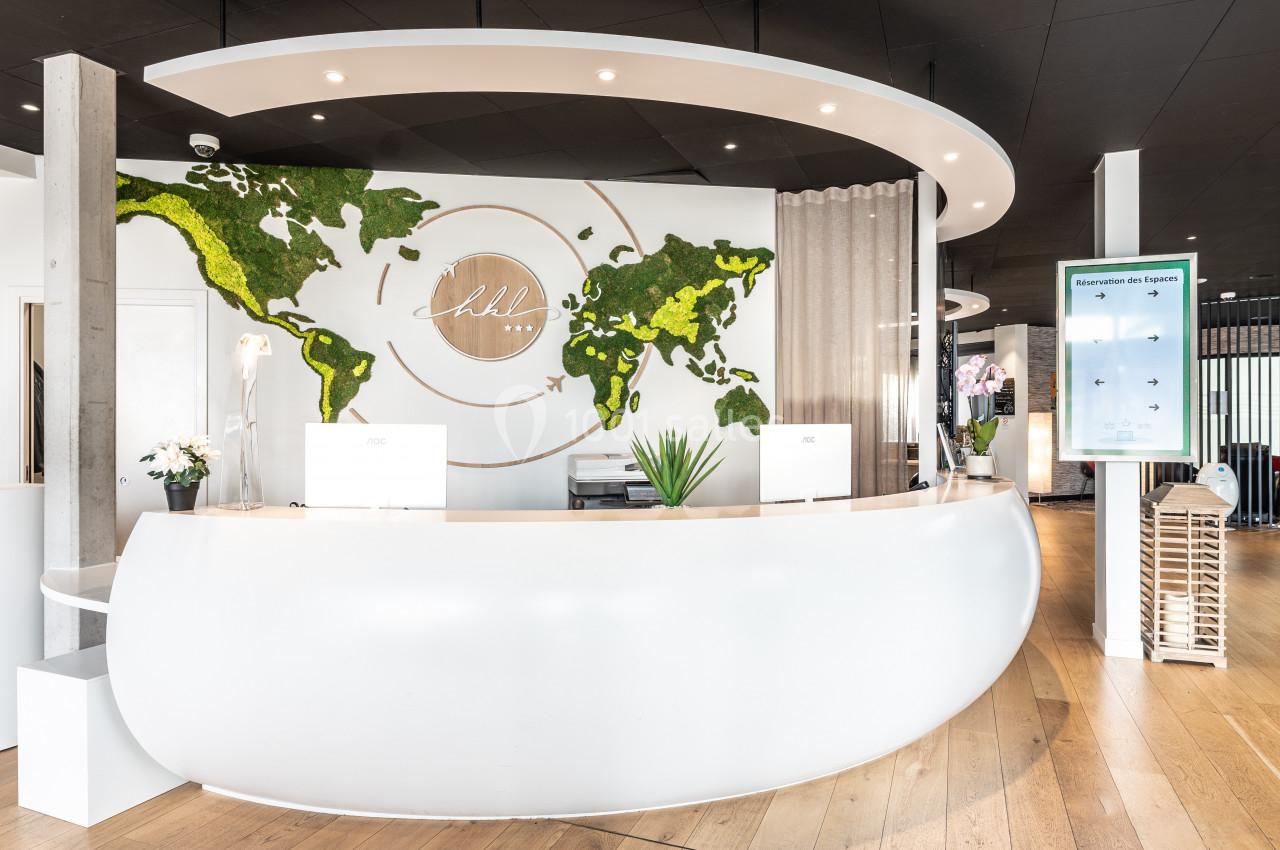 Comptoir d'accueil moderne avec décoration murale représentant une carte du monde en mousse végétale.