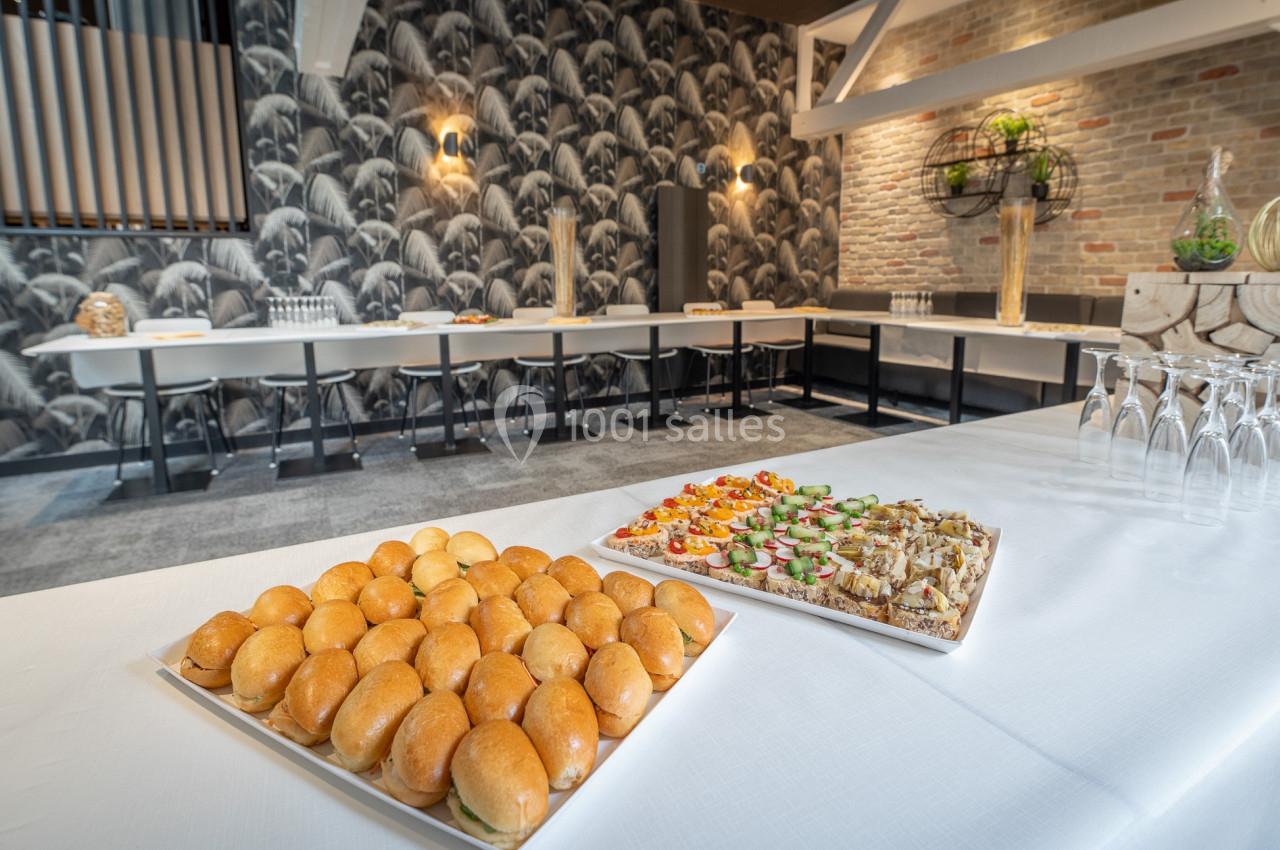 Plateaux de mini-sandwichs et amuse-bouches disposés sur une table dans une salle de réception élégante.