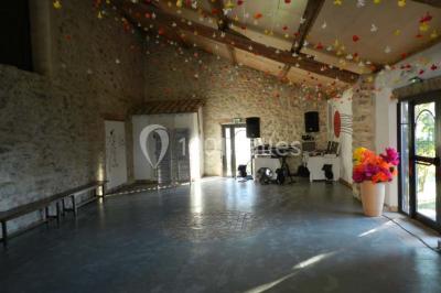 Salle de réception décorée avec des tables rondes dressées, des chaises blanches et des plantes entourant l'espace.