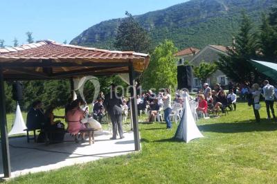 Salle de réception décorée avec des tables rondes dressées, des chaises blanches et des plantes entourant l'espace.