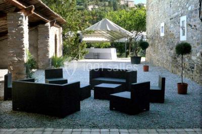 Salle de réception décorée avec des tables rondes dressées, des chaises blanches et des plantes entourant l'espace.