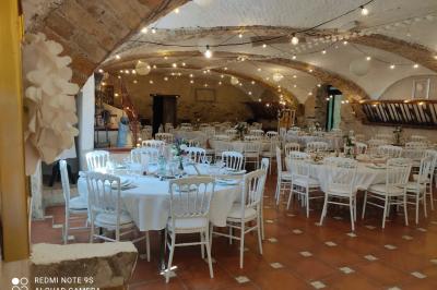 Salle de réception décorée avec des tables rondes dressées, des chaises blanches et des plantes entourant l'espace.