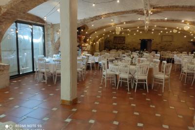 Salle de réception décorée avec des tables rondes dressées, des chaises blanches et des plantes entourant l'espace.