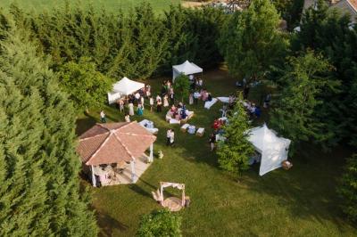Salle de réception décorée avec des tables rondes dressées, des chaises blanches et des plantes entourant l'espace.