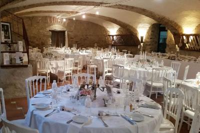 Salle de réception décorée avec des tables rondes dressées, des chaises blanches et des plantes entourant l'espace.