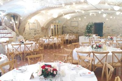 Salle de réception décorée avec des tables rondes dressées, des chaises blanches et des plantes entourant l'espace.