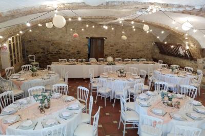 Salle de réception décorée avec des tables rondes dressées, des chaises blanches et des plantes entourant l'espace.
