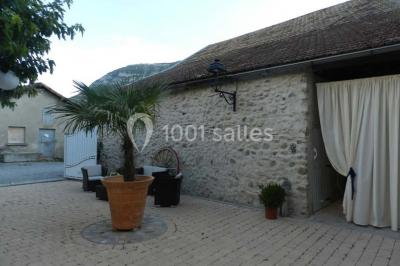 Salle de réception décorée avec des tables rondes dressées, des chaises blanches et des plantes entourant l'espace.