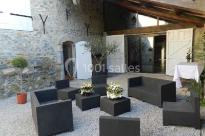 Salle de réception décorée avec des tables rondes dressées, des chaises blanches et des plantes entourant l'espace.