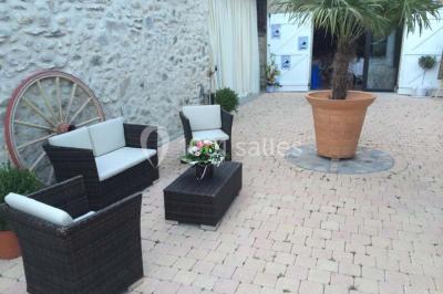 Salle de réception décorée avec des tables rondes dressées, des chaises blanches et des plantes entourant l'espace.