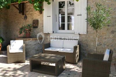 Salle de réception décorée avec des tables rondes dressées, des chaises blanches et des plantes entourant l'espace.