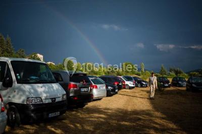 Salle de réception décorée avec des tables rondes dressées, des chaises blanches et des plantes entourant l'espace.