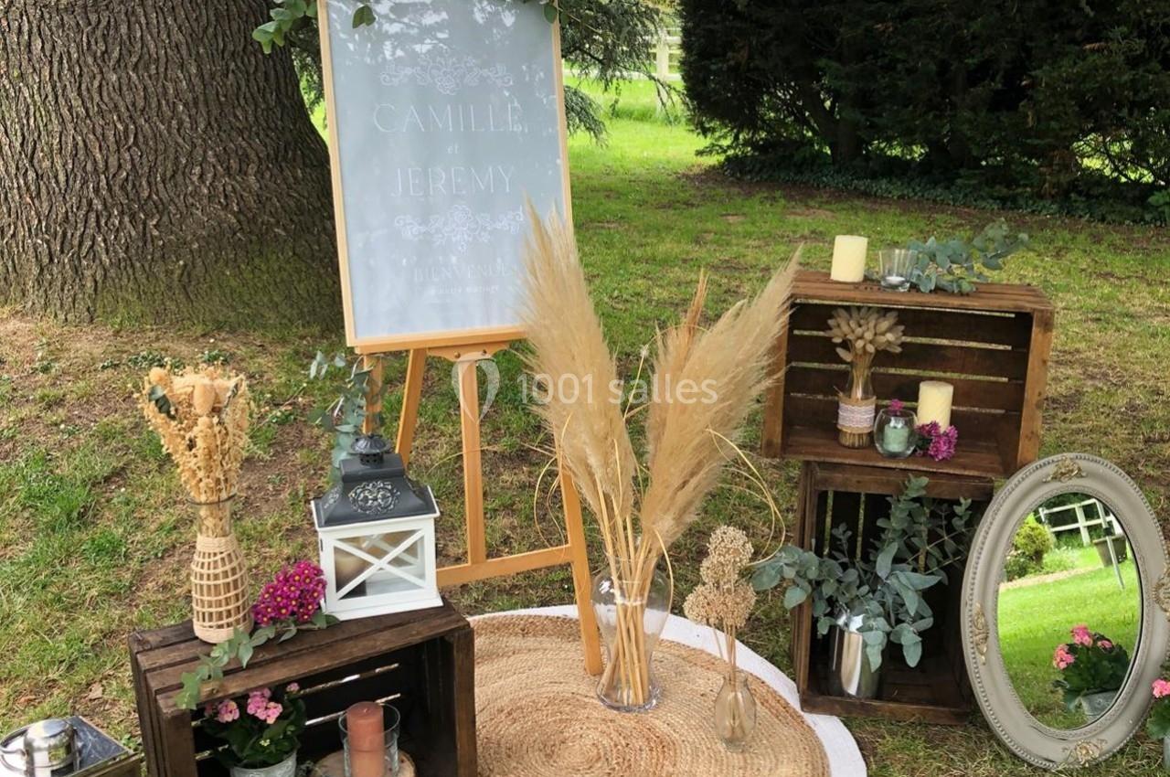 Décoration champêtre avec fleurs séchées, lanternes, miroirs et caisses en bois disposés sur un tapis en extérieur.