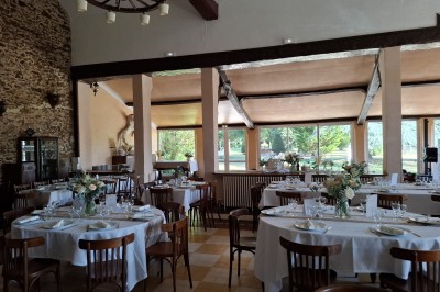 Grande table dressée avec nappes blanches, serviettes rouges, verres et couverts, décorée de bougies et fleurs au centre.