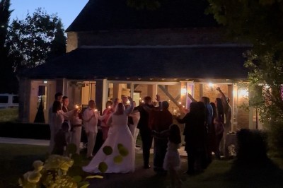 Grande table dressée avec nappes blanches, serviettes rouges, verres et couverts, décorée de bougies et fleurs au centre.