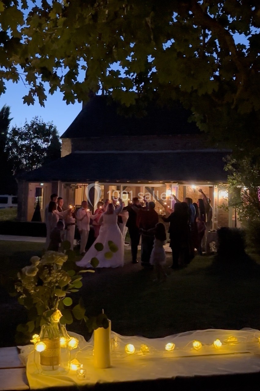 Groupe de personnes dansant en soirée devant un bâtiment éclairé, avec une table décorée au premier plan.