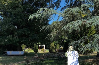 Grande table dressée avec nappes blanches, serviettes rouges, verres et couverts, décorée de bougies et fleurs au centre.