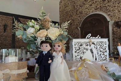 Grande table dressée avec nappes blanches, serviettes rouges, verres et couverts, décorée de bougies et fleurs au centre.