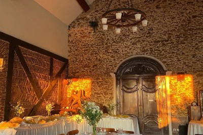 Grande table dressée avec nappes blanches, serviettes rouges, verres et couverts, décorée de bougies et fleurs au centre.