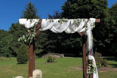 Grande table dressée avec nappes blanches, serviettes rouges, verres et couverts, décorée de bougies et fleurs au centre.