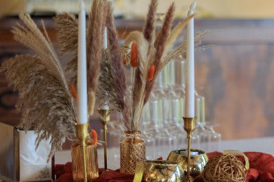 Grande table dressée avec nappes blanches, serviettes rouges, verres et couverts, décorée de bougies et fleurs au centre.