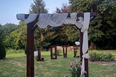 Grande table dressée avec nappes blanches, serviettes rouges, verres et couverts, décorée de bougies et fleurs au centre.