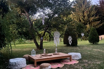 Grande table dressée avec nappes blanches, serviettes rouges, verres et couverts, décorée de bougies et fleurs au centre.