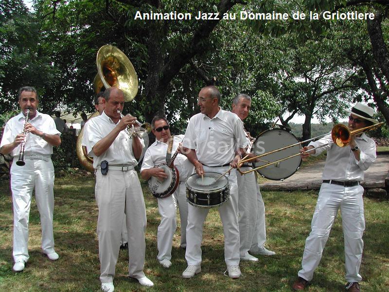 Musiciens en tenue blanche jouant des instruments de jazz en plein air devant des arbres.