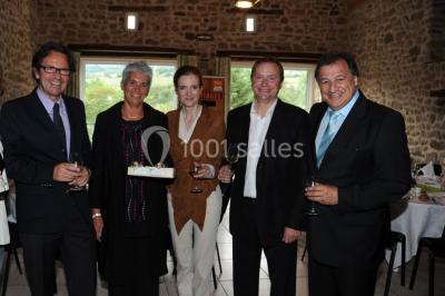Un groupe de personnes posant debout dans une pièce avec des murs en pierre et une table en arrière-plan.