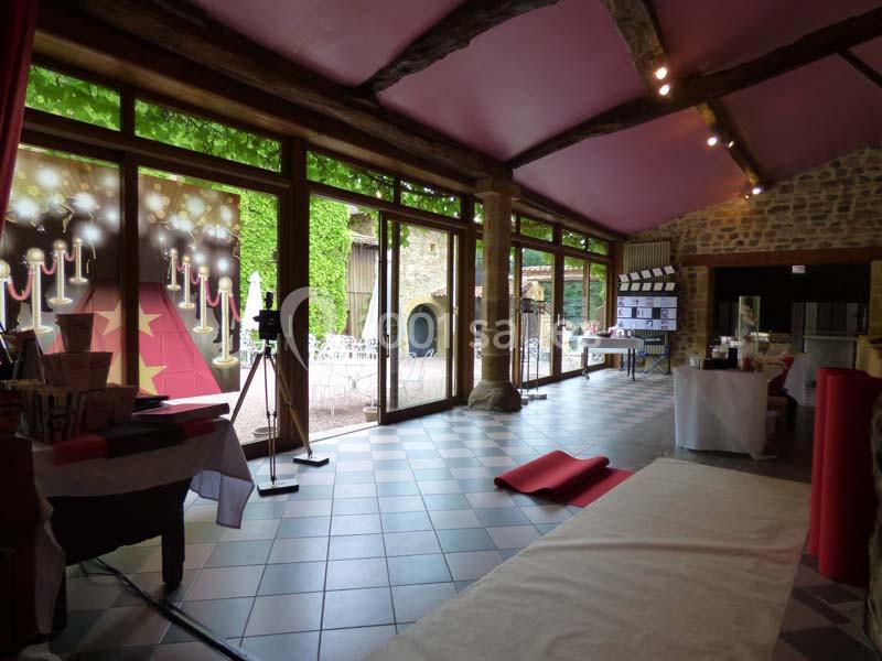 Salle lumineuse avec baies vitrées, décorée pour un événement avec tapis rouge, affiches et matériel de réception.