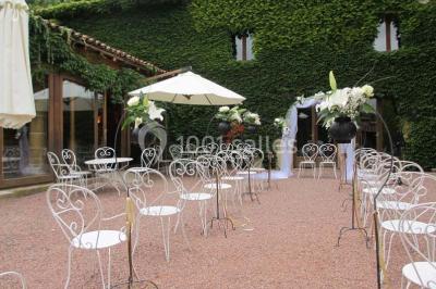 Décoration florale composée de roses, pivoines et feuillage, accrochée à une structure blanche en extérieur.