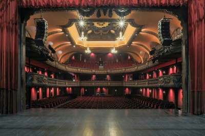 Hall spacieux avec sol en mosaïque, arches illuminées et tables décorées, éclairage chaleureux et ambiance élégante.