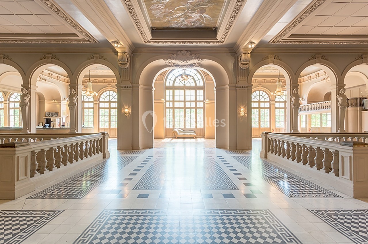 Intérieur lumineux d'un hall élégant avec arches, balustrades et carrelage décoratif, baigné de lumière naturelle.