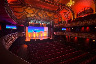 Hall spacieux avec sol en mosaïque, arches illuminées et tables décorées, éclairage chaleureux et ambiance élégante.