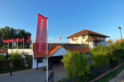 Structure de jeux en plein air avec toboggan et modules d'escalade, installée sur un sol sablonneux près d'une clôture.