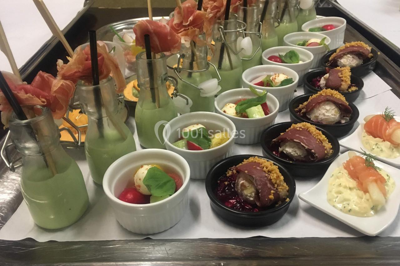 Plateau de verrines et amuse-bouches variés, incluant des légumes, viandes, poissons et sauces, présenté pour un buffet.