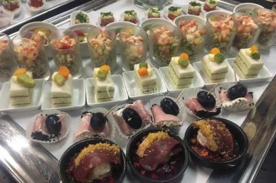 Structure de jeux en plein air avec toboggan et modules d'escalade, installée sur un sol sablonneux près d'une clôture.