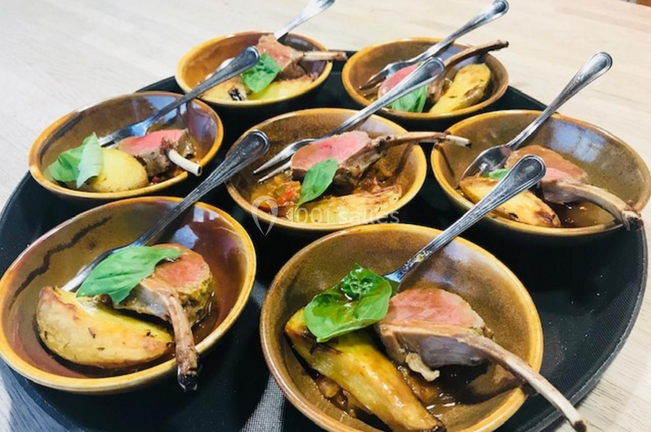 Assiettes individuelles contenant des côtelettes d'agneau, légumes rôtis et garniture de basilic, présentées sur un plateau.