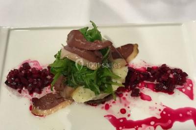 Structure de jeux en plein air avec toboggan et modules d'escalade, installée sur un sol sablonneux près d'une clôture.