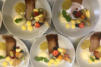 Structure de jeux en plein air avec toboggan et modules d'escalade, installée sur un sol sablonneux près d'une clôture.