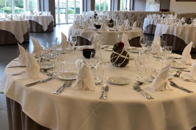 Structure de jeux en plein air avec toboggan et modules d'escalade, installée sur un sol sablonneux près d'une clôture.