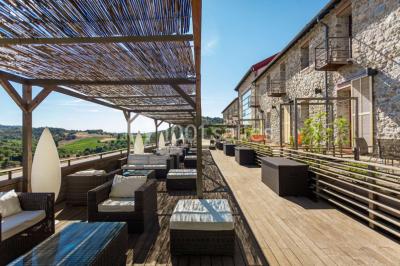 Miniature Location salle Bélesta (Pyrénées-Orientales) - Domaine Riberach #3 Bain à remous éclairé en bleu, entouré de pierres sombres, avec un panier de pétales rouges au premier plan.