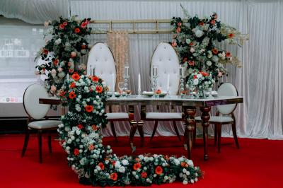 Salle de réception élégante avec des tables dressées, des verres à pied et un lustre lumineux au plafond.