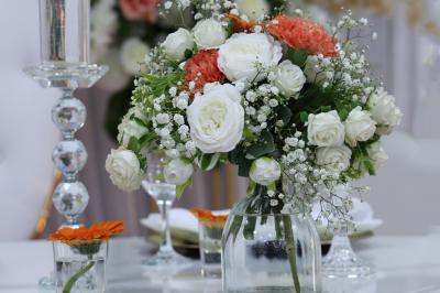 Salle de réception élégante avec des tables dressées, des verres à pied et un lustre lumineux au plafond.