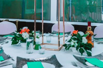 Salle de réception élégante avec des tables dressées, des verres à pied et un lustre lumineux au plafond.