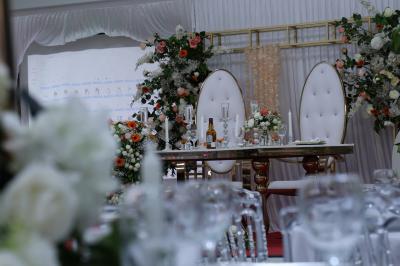 Salle de réception élégante avec des tables dressées, des verres à pied et un lustre lumineux au plafond.