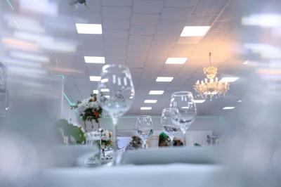Salle de réception élégante avec des tables dressées, des verres à pied et un lustre lumineux au plafond.